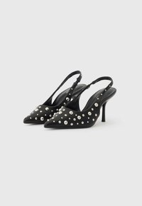 Escarpins slingbacks noirs à bout pointu, ornés de clous argentés de tailles variées sur la surface. Talon fin et texture lisse.