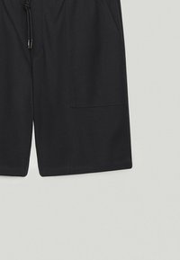 Shorts noirs en tissu léger, dotés d'une taille ajustable avec cordon de serrage, de poches latérales et d'une coupe décontractée.