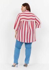 Gestreiftes Button-up-Hemd in Rot, Weiß und Blau, mit Dreiviertelärmeln und abgerundetem Saum, kombiniert mit hellblauen Jeans und High Heels.