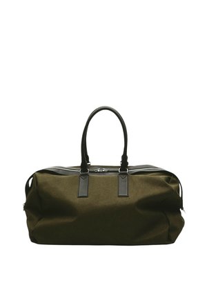 Grand sac polochon en tissu vert olive avec poignées en cuir noir et fermeture éclair sur le dessus, sur fond blanc.