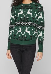 Grüner Strickpullover mit weißen Rentieren, Schneeflocken und dem Text "FROHE WEIHNACHTEN!" in Schwarz. Gerippte Bündchen und Saum, mit Rundhalsausschnitt.