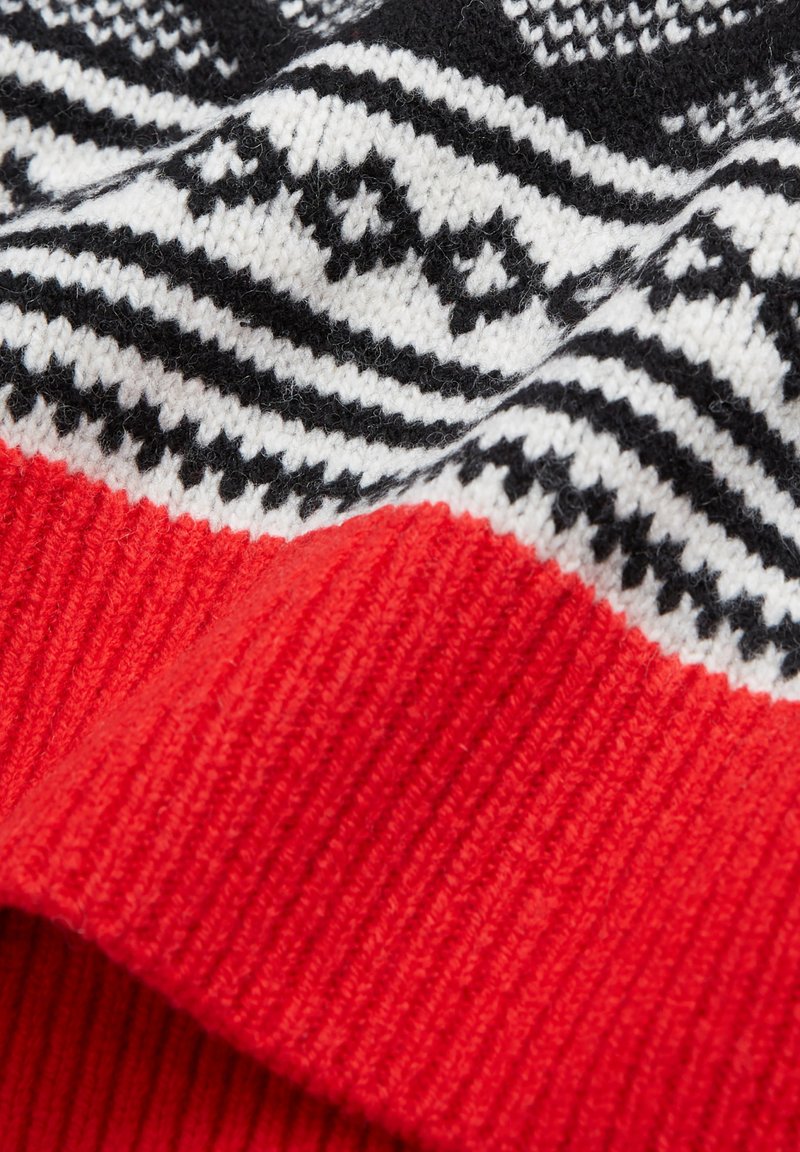 Strickpullover mit einem schwarz-weißen geometrischen Muster und einem leuchtend roten Rippenbund. Weiche Textur mit einem gemütlichen Aussehen.