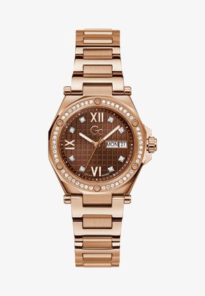 Sat s ružičastog zlata s osmostranim kućištem, smeškim teksturiranim brojčanikom, bijelim oznakama sati, prikazom datuma i kristalnim akcentima na bezelu.