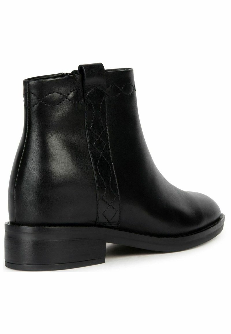 Bottines noires en cuir avec un bout arrondi, fermeture éclair sur le côté et accents de couture décorative. Le talon bas empilé offre de la stabilité.