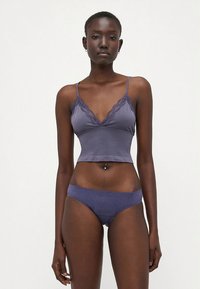 Set de lenjerie violet format dintr-un bralette cu dantelă și chiloți hipster cu model, ambele realizate dintr-un material neted și elastic.