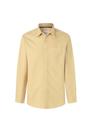 Šviesiai geltonas ilgomis rankovėmis marškinis, pagamintas iš medvilnės. Pasižymi mygtukų užsegimu ant apykaklės, priekyje esančia kišenė ir nepastebima prekės ženklo etikete šone.