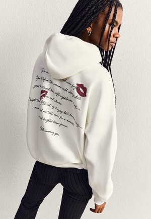 White hooded sweatshirt featuring burgundy lip prints and handwritten-style text on the back. Regular fit with ribbed cuffs and hem.