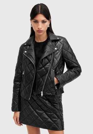 Black quilted leather biker jacket with silver zippers, snap collar, and side pockets, paired with a matching quilted skirt.