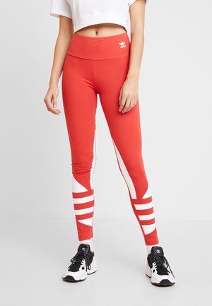 Rode sportleggings met een hoge tailleband en witte strepen aan de zijkanten, gemaakt van rekbaar materiaal.