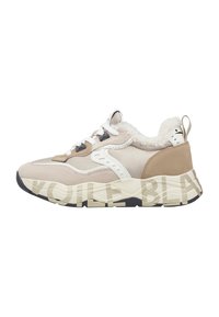 Sneaker beige e crema con lacci bianchi, suola nera e marrone, rivestimento in shearling, pannelli in suede e pelle, e nome del marchio sulla suola intermedia.