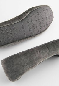 Grå stoftøfler med en blød, tekstureret overdel og tekstureret gummisål, der har et polstret design for komfort.