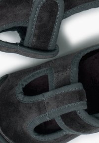 Scarpe in suede nero con design aperto e tagli tondeggianti. Texture morbida, cuciture rinforzate e dettagli grigi lungo i bordi.