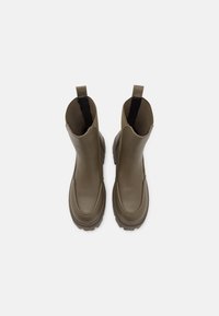 Botas de tobillo impermeables marrones con un acabado suave, puntera redondeada, cuello acolchado y tiradores a los lados para facilitar el calzado. Suela texturizada.