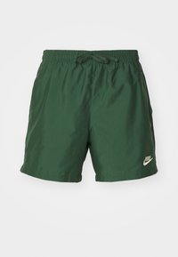 Gröna shorts gjorda av glatt, lättviktigt tyg. Har en elastisk midja med dragsko och en liten vit Nike-logga på framsidan.