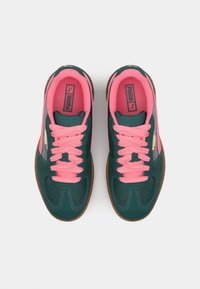 Dark green sneakers with pink laces and accents. Features a textured surface, gum sole, and PUMA logo on the side. Classic design.