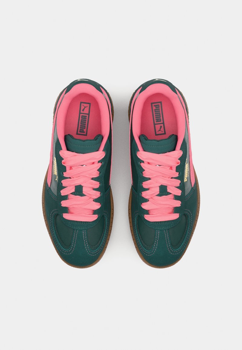 Zapatillas de deporte verde oscuro con cordones y acentos rosas. Presentan una superficie texturizada, suela de goma y el logo de PUMA en el lateral. Diseño clásico.
