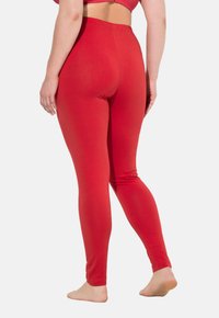 Leggings rossi realizzati in tessuto morbido e elasticizzato. Presentano una vita alta e una texture liscia, con una vestibilità aderente che si estende fino alle caviglie.