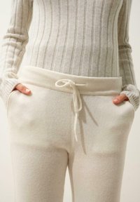 Krämfärgade stickade byxor med dragsko i midjan, med fickor och en mjuk textur, tillsammans med en ribbad långärmad tajt topp.