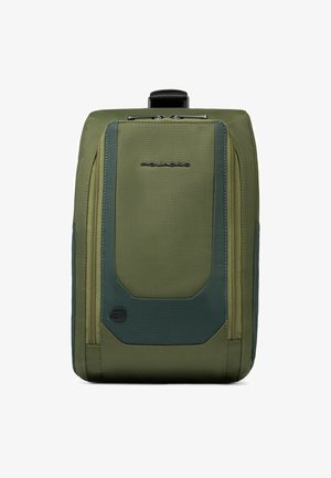 Zaino in tessuto verde con un design geometrico, dotato di tasche frontali con cerniera, materiale testurizzato e maniglia superiore per il trasporto.