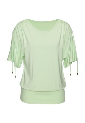 Blouse vert clair avec manches courtes froncées et cordons réglables, ourlet large ajusté à la taille.