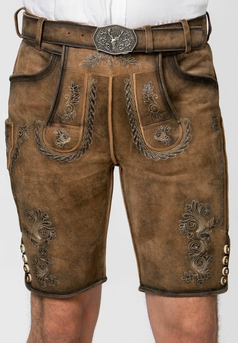 Skórzane lederhosen w kolorze brązowym, z srebrnymi haftami, ozdobnymi kieszeniami oraz metalową klamrą z motywem jelenia. Dodatkowe guziki po bokach.