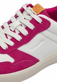 Sneaker con pannelli in pelle bianca e suede rosa, con lacci bianchi e un'etichetta arancione. Il design presenta una texture liscia e una forma tondeggiante.