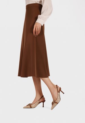 Gonna midi marrone abbinata a sandali beige con tacco a slingback, caratterizzati da un motivo texturizzato, punta affusolata e un tacco piccolo. Tessuto a superficie liscia.