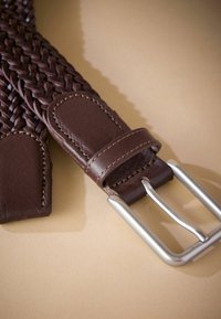 Geflochtener brauner Ledergürtel mit einer silbernen Metallschnalle. Glatte Oberfläche mit detaillierter Naht an den Lederenden.