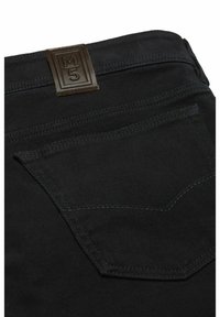 Hintertasche von schwarzen Jeans aus Denim mit dunkler Naht und einem braunen rechteckigen Lederpatch, das mit "M5" auf dem Bund geprägt ist.