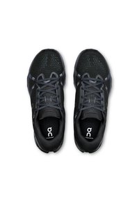 Chaussures de sport noires avec une tige en maille, un bout renforcé et des accents gris. Elles sont dotées d'une semelle intérieure rembourrée et de lacets plats pour un maintien sécurisé.