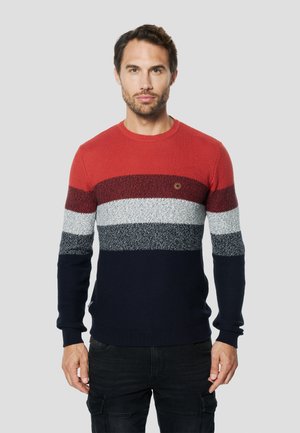 Jersey de punto con rayas en rojo, rojo oscuro, gris, blanco y azul marino. Cuello redondo, patrón de punto texturizado y un pequeño detalle de logo en el pecho.