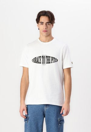 White cotton t-shirt with short sleeves featuring a black graphic print reading "TERRACE TO THE PITCH" across the chest. Relaxed fit.