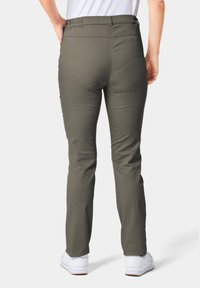 Olijfgroene broek met een soepele textuur, op maat gemaakt en met een elastische tailleband, gezien van de achterkant, gecombineerd met witte schoenen.