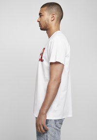 Hvid bomulds t-shirt med et farverigt grafisk print på forsiden. Korte ærmer og løs pasform, parret med lyseblå jeans.