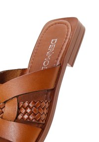 Sandale à enfiler en cuir marron avec détail de bride tressée et talon bloc sur fond blanc.