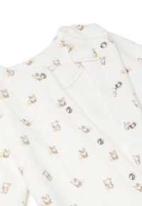 Cárdigan blanco para bebé, elaborado con una tela suave y con un estampado integral de conejitos y ositos de color marrón claro. En la parte delantera cuenta con cierres a presión plateados.