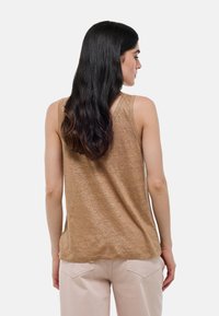 Top en tank marron, sans manches, fabriqué dans un tissu léger et texturé. Présente un ourlet incurvé et des bretelles étroites, vu de l'arrière.