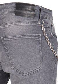 Grå denimjeans med et lærmerke, kjededetalj på beltesløyfen og tradisjonelt femlommesdesign med markert søm.