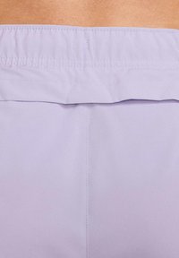 Tela de color púrpura claro con una cinturilla fruncida, textura suave y detalles de costura simples. El diseño es minimalista y sin adornos.