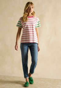 Puuvillane T-särk roosa ja rohelise triibuga, ümmargune kaelus, lühikesed varrukad. Kombineeritud siniste teksade ja rohelise õhukese jalanõuga. Lihtne ja lõdvestunud välimus.