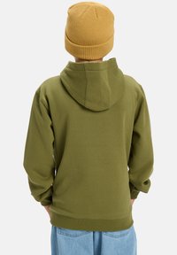 Vihreä oliivinvihreä huppari, jossa on puuvillasekoitus, huppu ja ribbikudotut hihansuut. Se on yhdistetty teksturoidun sinapin väriseen neulahuivipäähineeseen ja vaaleisiin farkkuihin.