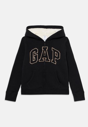 Sweat à zip noir avec doublure en polaire blanche, poches avant et grand logo "GAP" en contour sur la poitrine.
