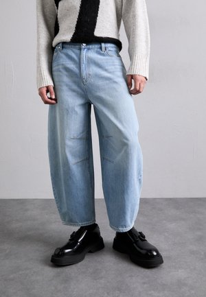 Heled sinised lai jalaga teksad, millel on kaks ristpistes üksikasja, koos mustade platvormkingade ja halli ja musta mustriga kudumiga.