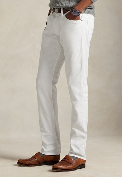 Calças de algodão branco com corte reto, cinco bolsos e costura em contraste. Combinadas com mocassins castanhos e meias cinzentas.