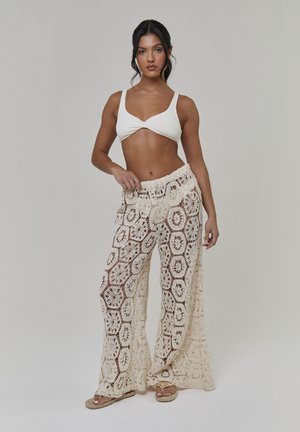 Pantaloni lavorati a uncinetto a rete aperta beige chiaro con un intricato motivo esagonale e design a gamba larga con vita elastica.