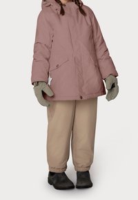 Veste matelassée rose avec capuche et fermeture éclair à l'avant. Pantalon beige élastiqué et gants gris complètent la tenue. Chaussures noires.