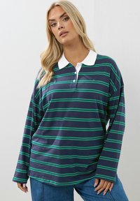 Marineblå långärmad polo t-shirt med vit krage och gröna ränder. Mjuk tyg med avslappnad passform och rundad nederkant. Stora knappar vid kragen.