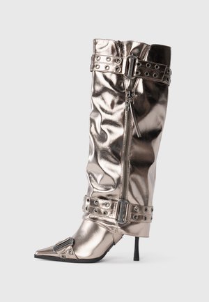 Metallic knee-high boot with a slim stiletto heel, pointed toe, zip closure, and studded buckle straps. Features a wrinkled texture.
