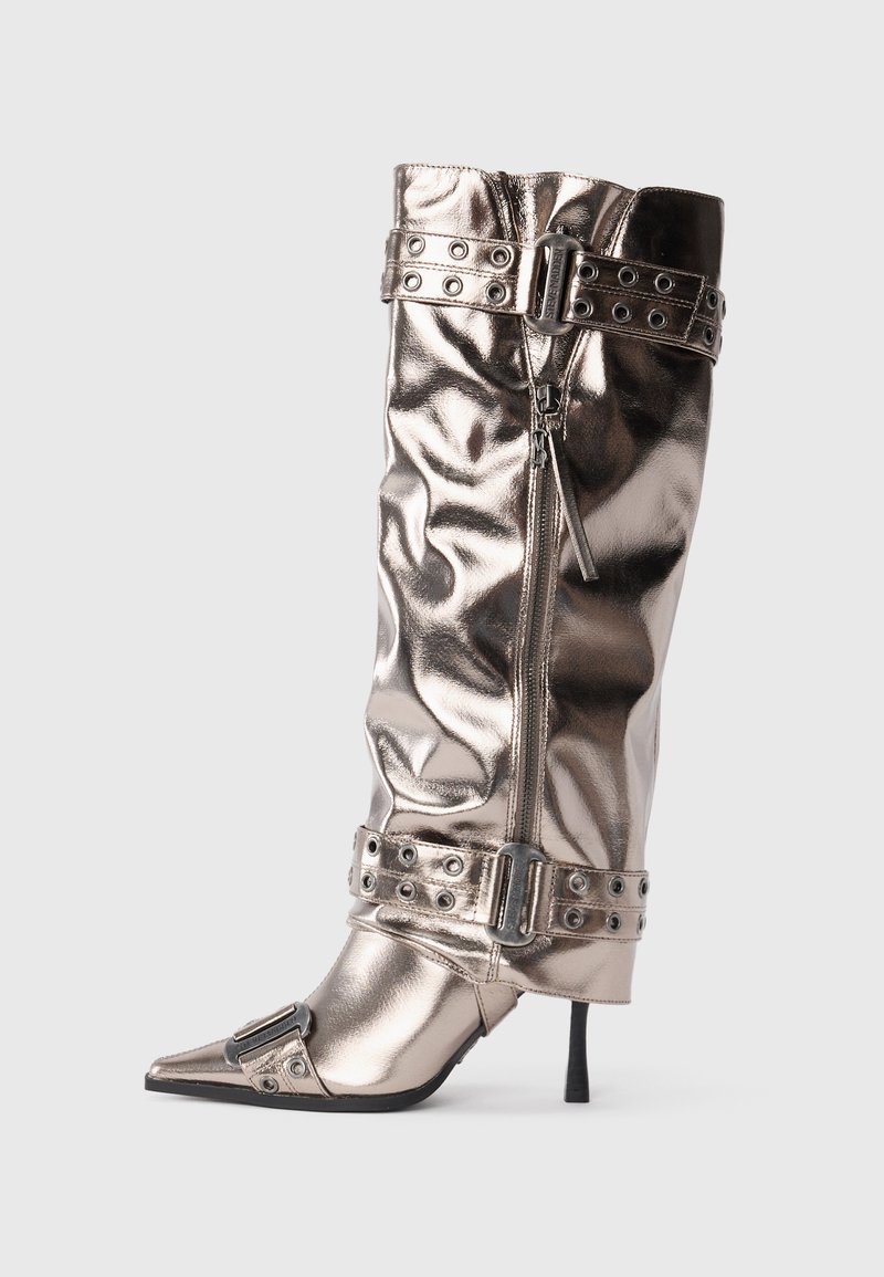 Botă metallică până la genunchi, cu un toc stiletto subțire, vârf ascuțit, închidere cu fermoar și curele cu catarame cu cuie. Prezintă o textură șifonată.