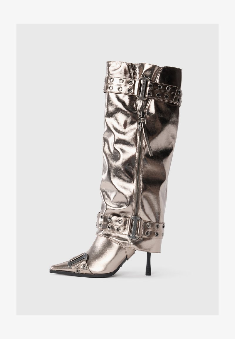 Stivale metallico alto fino al ginocchio con tacco a spillo sottile, punta appuntita, chiusura con zip e cinturini decorati con borchie. Presenta una texture rugosa.